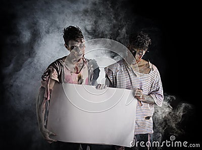 Two male zombies holding empty white banner Stock Photo