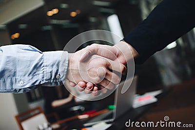 Two managers in casual clothing in meeting room handshakes after finding compromise Stock Photo