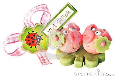 Two marzipan pigs with cloverleaf and good luck (in German) written on a background Stock Photo