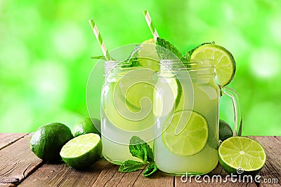 Two mason jars of limeade against a green outdoors background Stock Photo