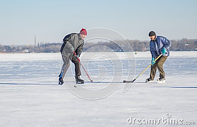 Two mature man fighting for the pack while playing amateur hockey on a frozen river Dnepr in Ukraine Editorial Stock Photo