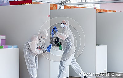 Two medical workers in white protective suit disinfect and clean public place with spray sanitizer to stop spreading virus Editorial Stock Photo