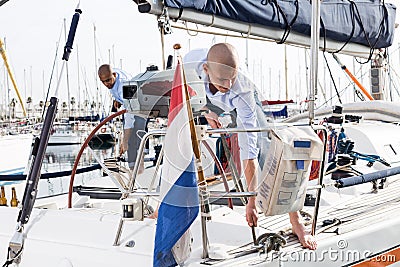 Two men in blue shirts and jeans working on sailing yacht in the port Stock Photo