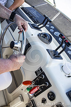 Two men on a boat, with hands and arms showing - one man drives and operates at cockpit and the other is relaxing and watching - u Stock Photo