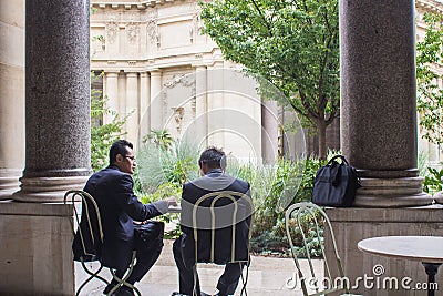 Two men in business suits confer at a cafe table in the courtyard of the Petit Palais, Paris Editorial Stock Photo