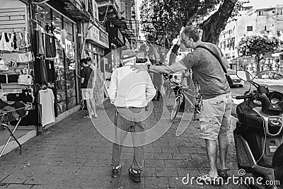 Two men in casual attire standing side by side on a sidewalk in front of bicycles. Editorial Stock Photo