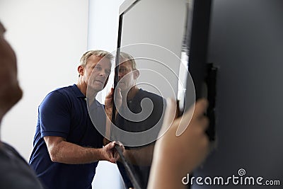 Two Men Fitting Flat Screen Television To Wall Stock Photo