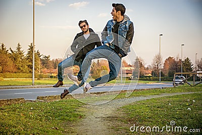 Two Men Leaping in Unison with Hands in Pockets Stock Photo