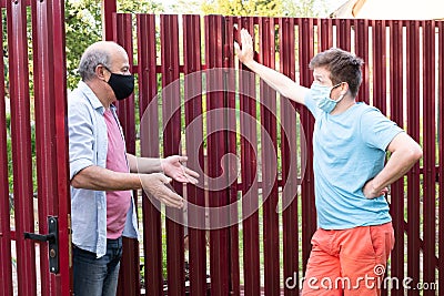 Two men in medical mask speaking to each other, discuss problems on sunny day Stock Photo