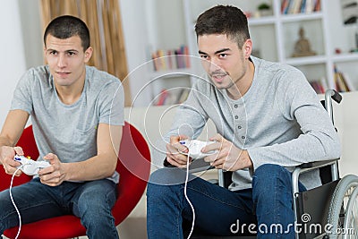 Two men playing computer game one in wheelchair Stock Photo