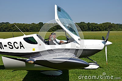 Two men sit into ultralight propeller-driven airplane and get ready for taking off Editorial Stock Photo