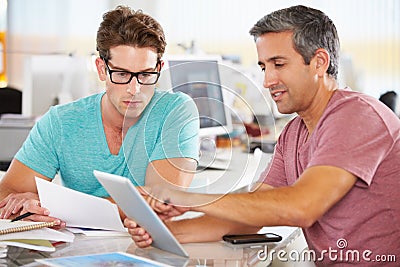 Two Men Using Tablet Computer In Creative Office Stock Photo