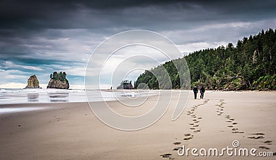 Two men walking on beach with footprints in the sand Editorial Stock Photo