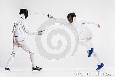 The two men wearing fencing suit practicing with sword against gray Stock Photo