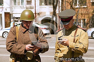 Two men wearing vintage military uniform, texting on smartphones Editorial Stock Photo