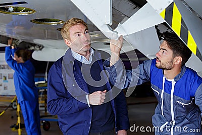 two men working under airplane Stock Photo