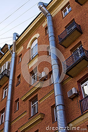 Two metal air ventilating tubes run along the facade of a brick building Editorial Stock Photo