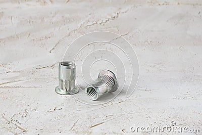 Two metal grey river nuts for hard internal thread for thin units on left part of oblong horizontal shot textured cement Stock Photo