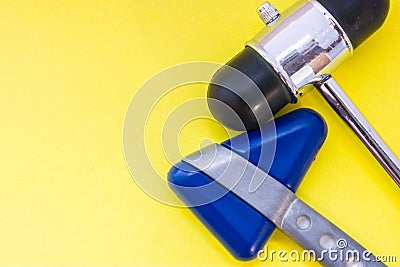 Two metal neurological rubber hammers to check or test for nerve reflexes are on yellow background top view. Concept picture idea Stock Photo