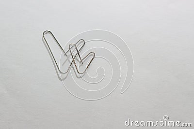 Two metal paper clips in the form of two checkmarks on a white paper sheet. Two hearts made of paper clips on a white background. Stock Photo