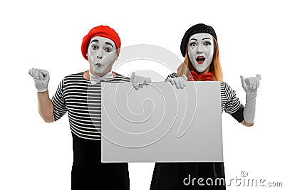 Two mimes holding a big blank board and leaning on invisible wall Stock Photo
