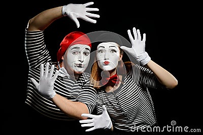 Two mimes leaning on imaginary wall with hands in white gloves Stock Photo
