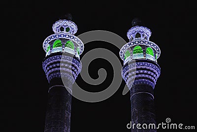 Two Minarets of an Iranian mosque are illuminated by colorful light at night. Stock Photo