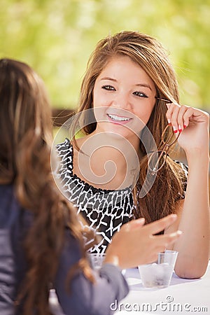 Two Mixed Race Teen Girlfriends Talking Over Drinks Outdoors Stock Photo