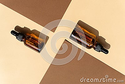 Two mockup of dropper bottle are randomly located among two sheets of brown paper. Hard shadow from objects falls on surface of Stock Photo
