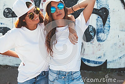 Models wearing plain tshirt and sunglasses posing over street wa Stock Photo