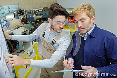 two modern aircraft engineers reading information on clipboard Stock Photo