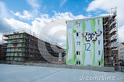 Two modern apartment block building, one with a facade scaffolding, artistically designed with a pattern of polygonal shapes, Stock Photo