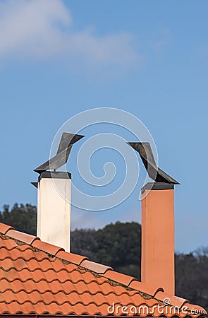 Two modern brick chimneys with wind cone on the roofs Stock Photo