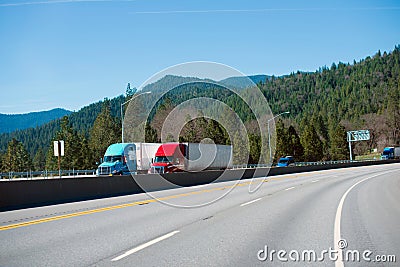 Two modern colored semi trucks driving highway turn side by side Stock Photo