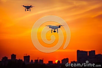 Two modern Remote Control Air Drones Fly with action cameras in dramatic orange sunset sk Stock Photo