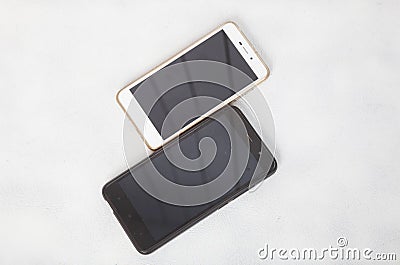Modern smartphones are lying on the white surface of the table Stock Photo