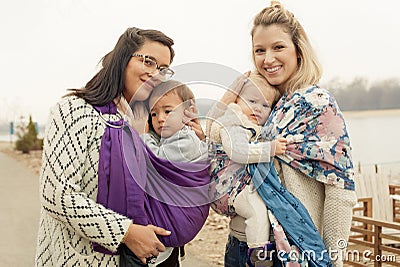 Two mothers with babies in baby carriers warp Stock Photo