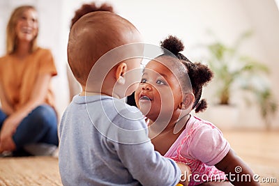 Two Mothers Meeting For Play Date With Babies At Home In Loft Apartment Stock Photo