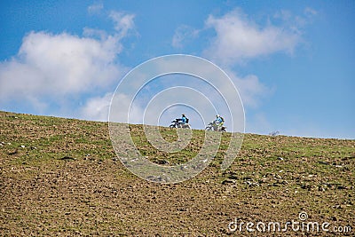 Two motorcyclist on the ridge of the hill against a blue sky Stock Photo