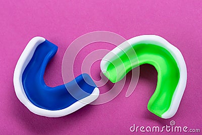 Two mouth guards, blue and green, on a lilac background, the concept of sports, boxing Stock Photo
