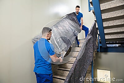 Two Movers Carrying Furniture On Staircase Stock Photo