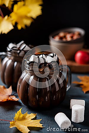 Two mugs of aroma hot chocolate with marshmallows on a dark background with autumn maple leaves. Concept cozy drink. Front view Stock Photo