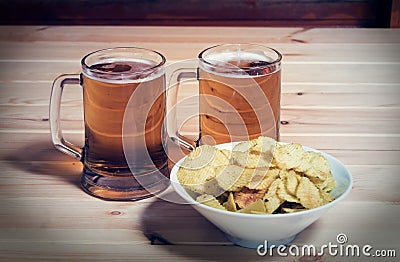 Two mugs of beer and bowl of potato chips Stock Photo