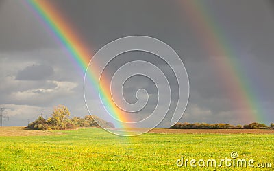 Two natural rainbow over green field after rain Stock Photo
