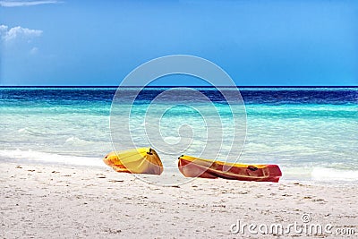 Two ocean kayaks on the beach with white sand and blue ocean Stock Photo