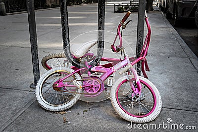 Two old girl`s bicycles, rusty and long forgotten, chained to a bike rack on a New York City street Stock Photo