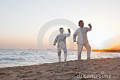 Two older people practicing Taijiquan on the beach at sunset, China Stock Photo