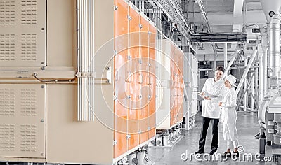 Two operator checks operation of vibrating machine for sifting flour from wheat and cereals, industry automatic modern Stock Photo