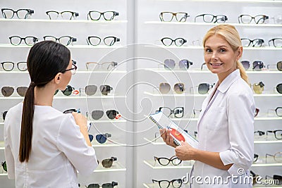 Two ophthalmologists wearing white coats standing in optical store Stock Photo