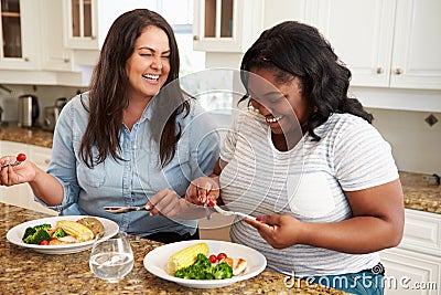 Two Overweight Women On Diet Eating Healthy Meal In Kitchen Stock Photo